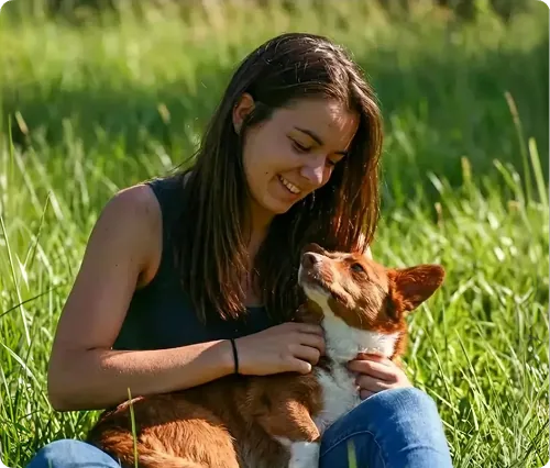 Cécile souriante aux côtés de son chien, en extérieur